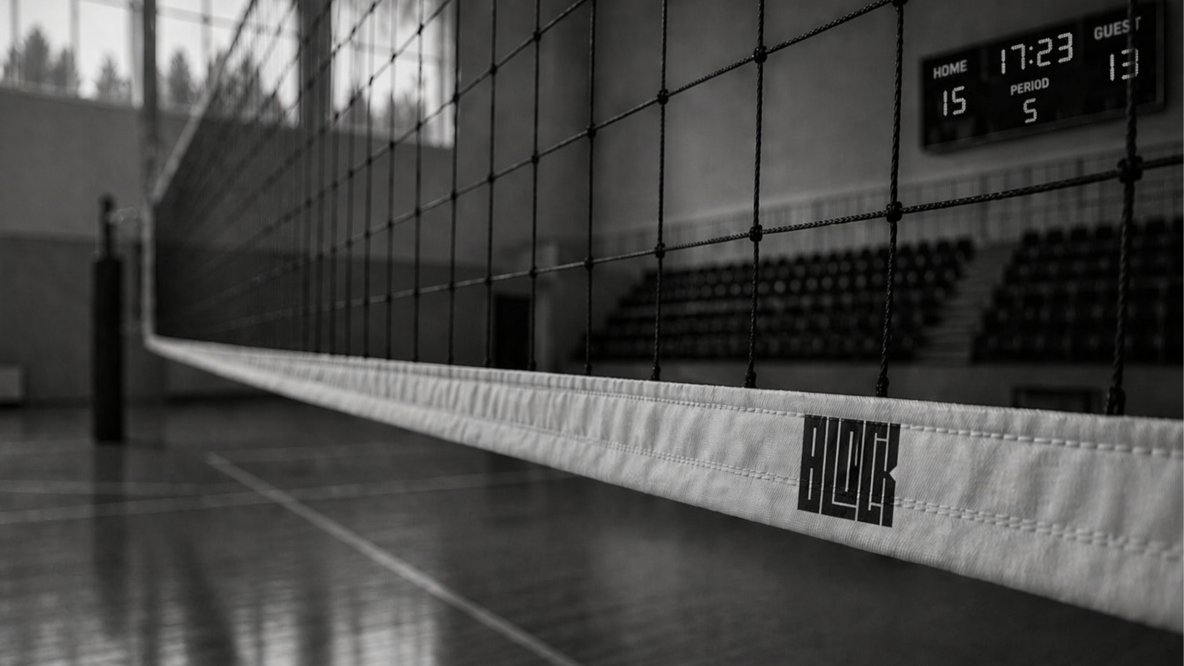 Indoor volleyball court with net and scoreboard in a gymnasium.